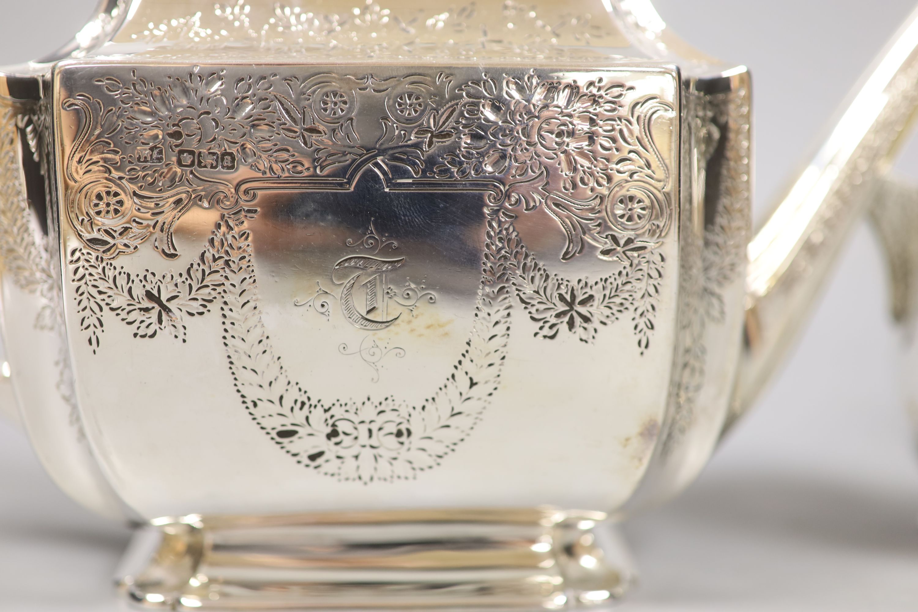 A silver three piece set, comprising teapot, twin-handled sugar basin and milk jug, with all-over chased decoration, London, 1893, by Atkins Brothers